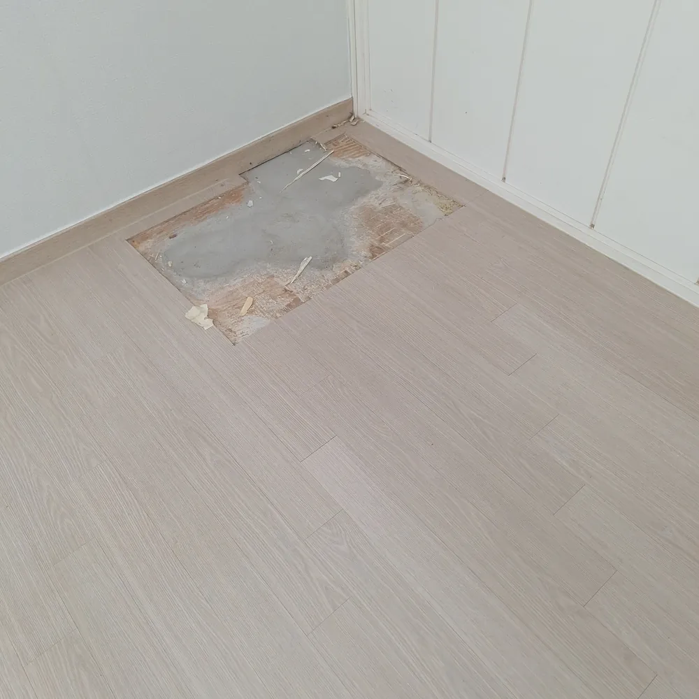 누수 공사 후 마루가 뜯겨 작은 사각 구멍처럼 바닥이 드러난 벽 붙박이장 앞 손상 부위 이전