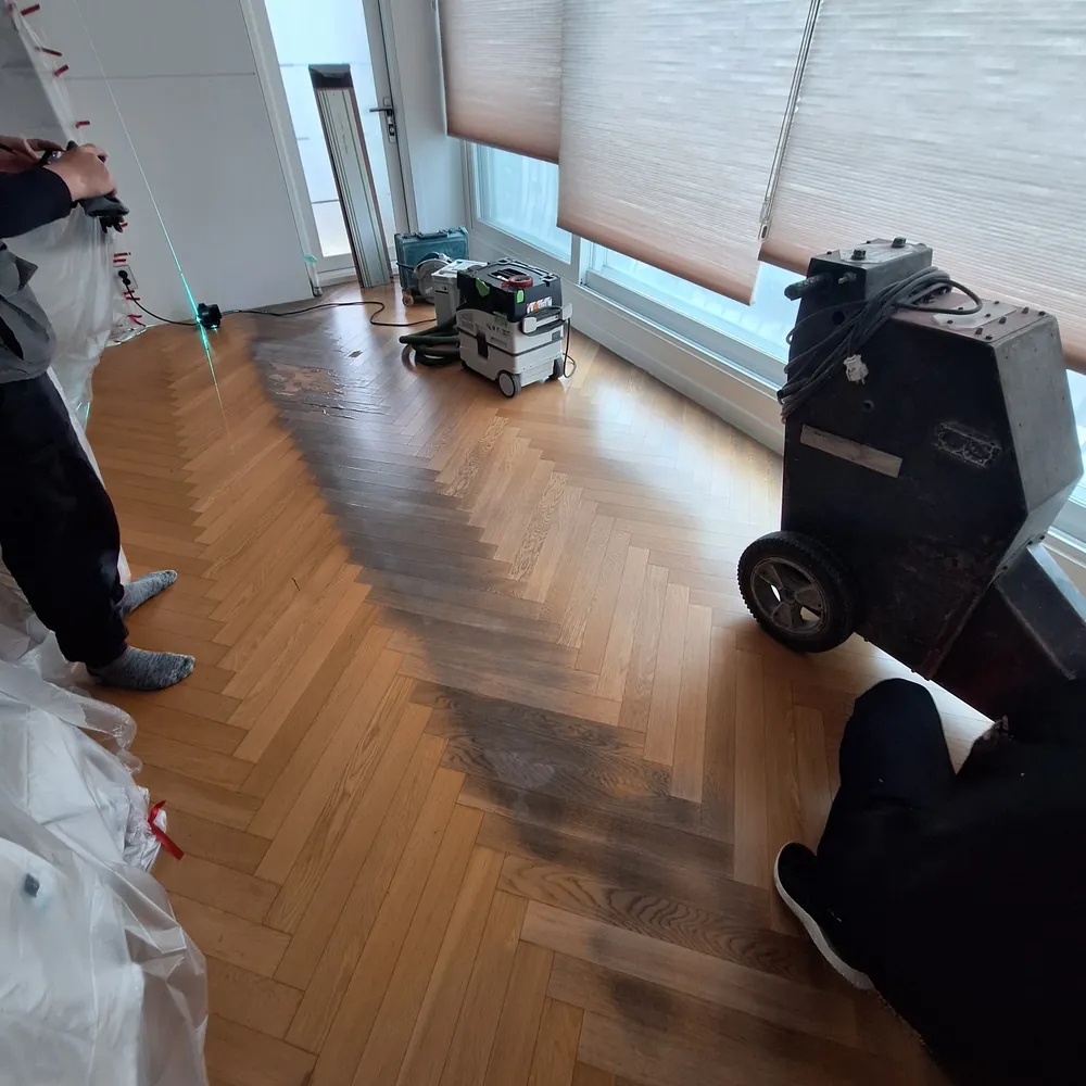 시공 후 연마기로 거실 확장부 마루 표면을 다듬는 작업자와 장비 진행 중